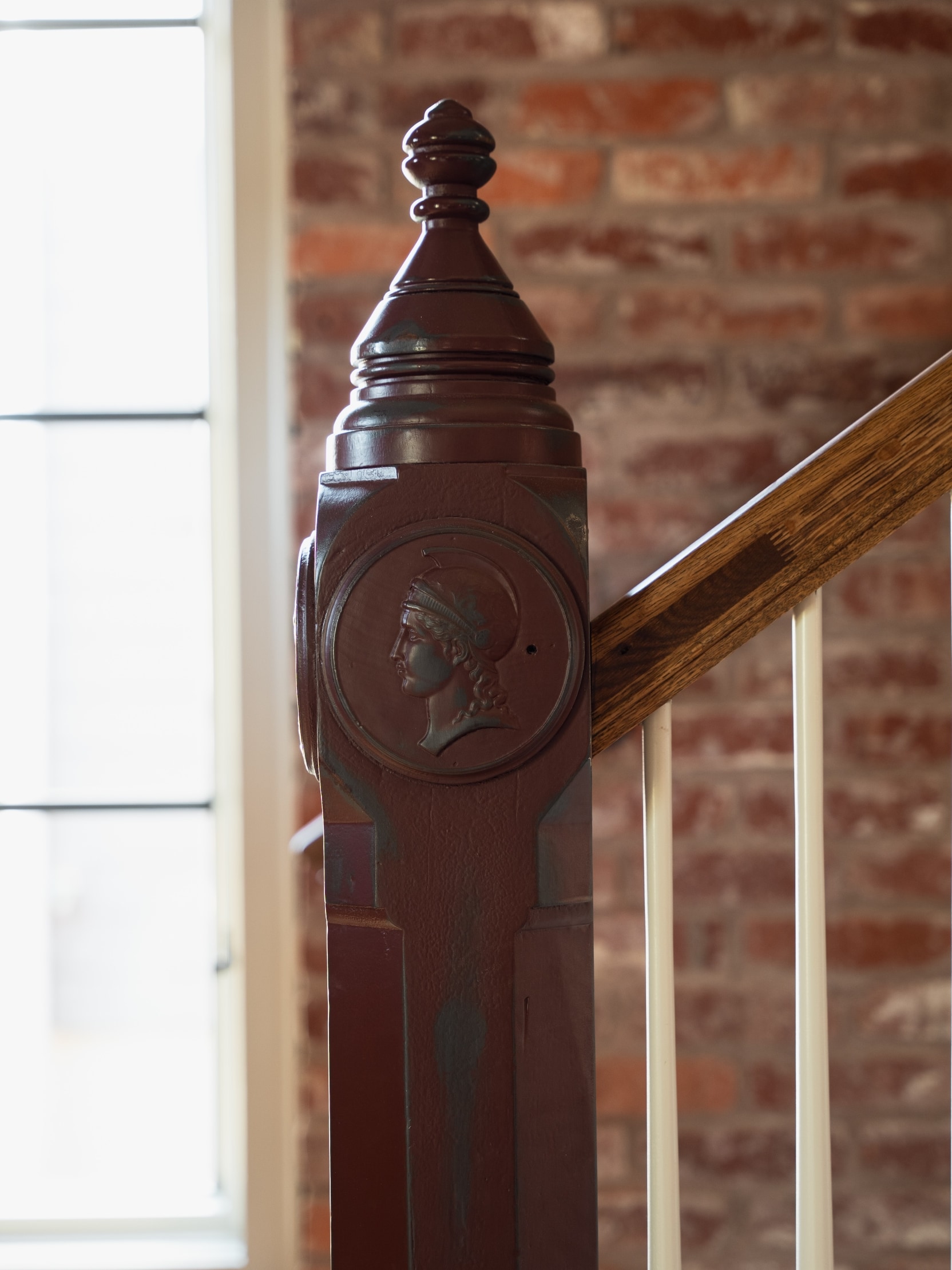 A handcrafted newel post with a classical medallion at the foot of an interior stair