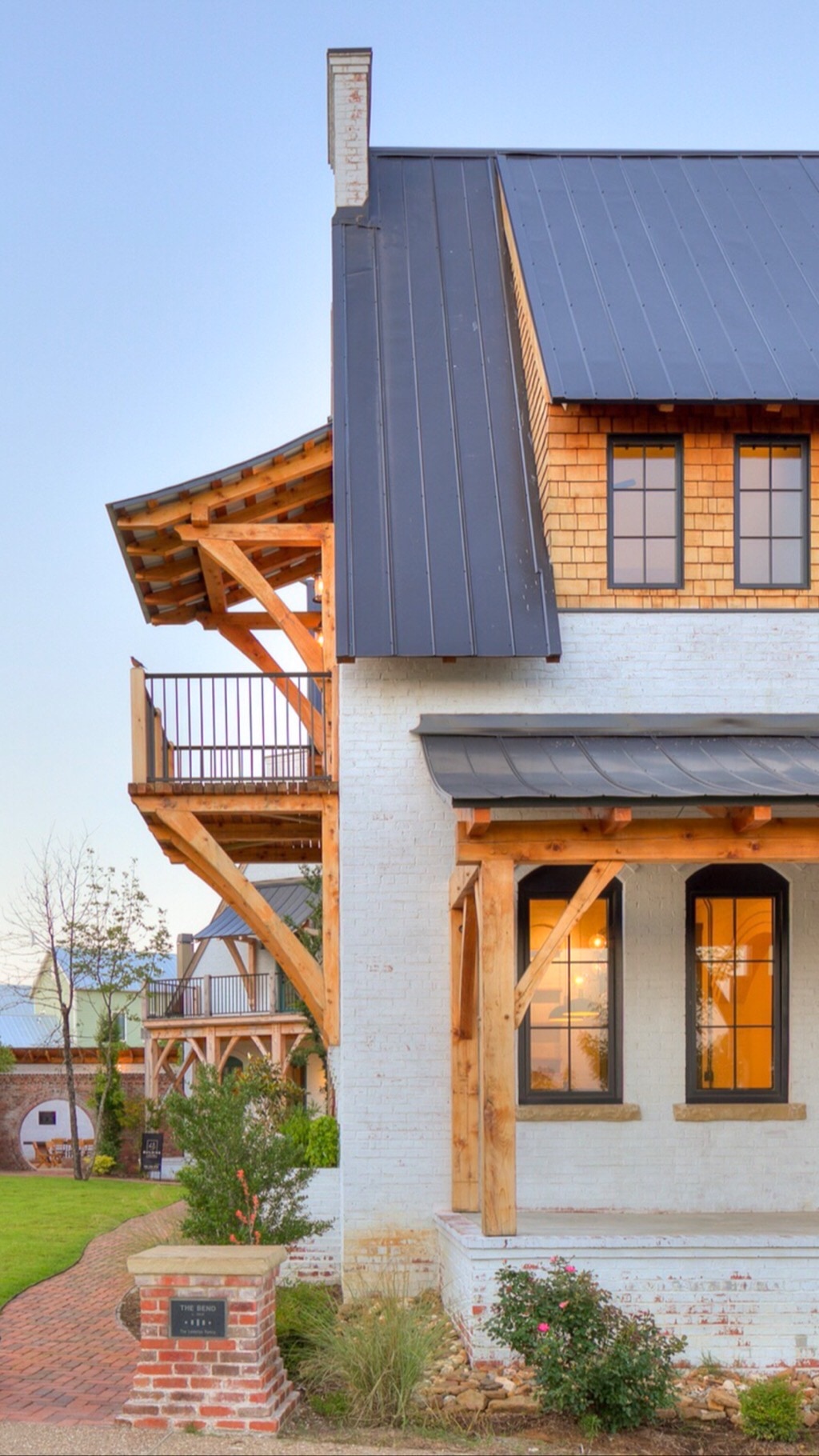 A finished home with exposed timber-frame brackets, painted brick, and a dark metal roof