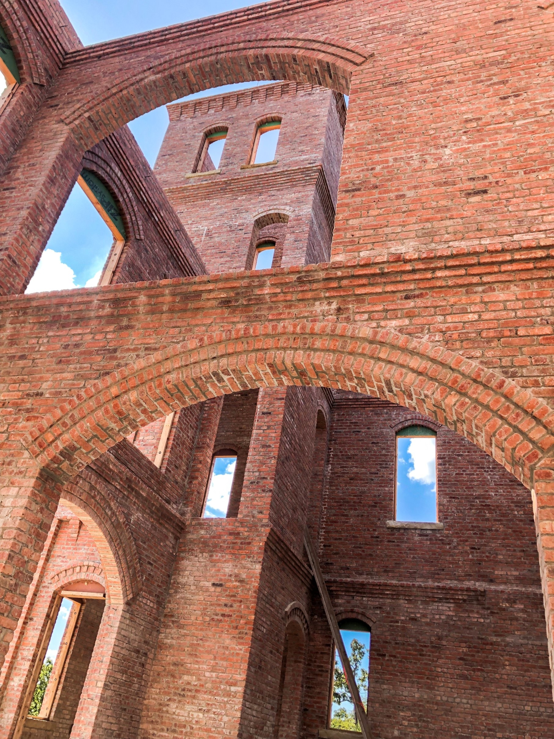 Structural brick masonry towers under construction, exposed arches open to the sky